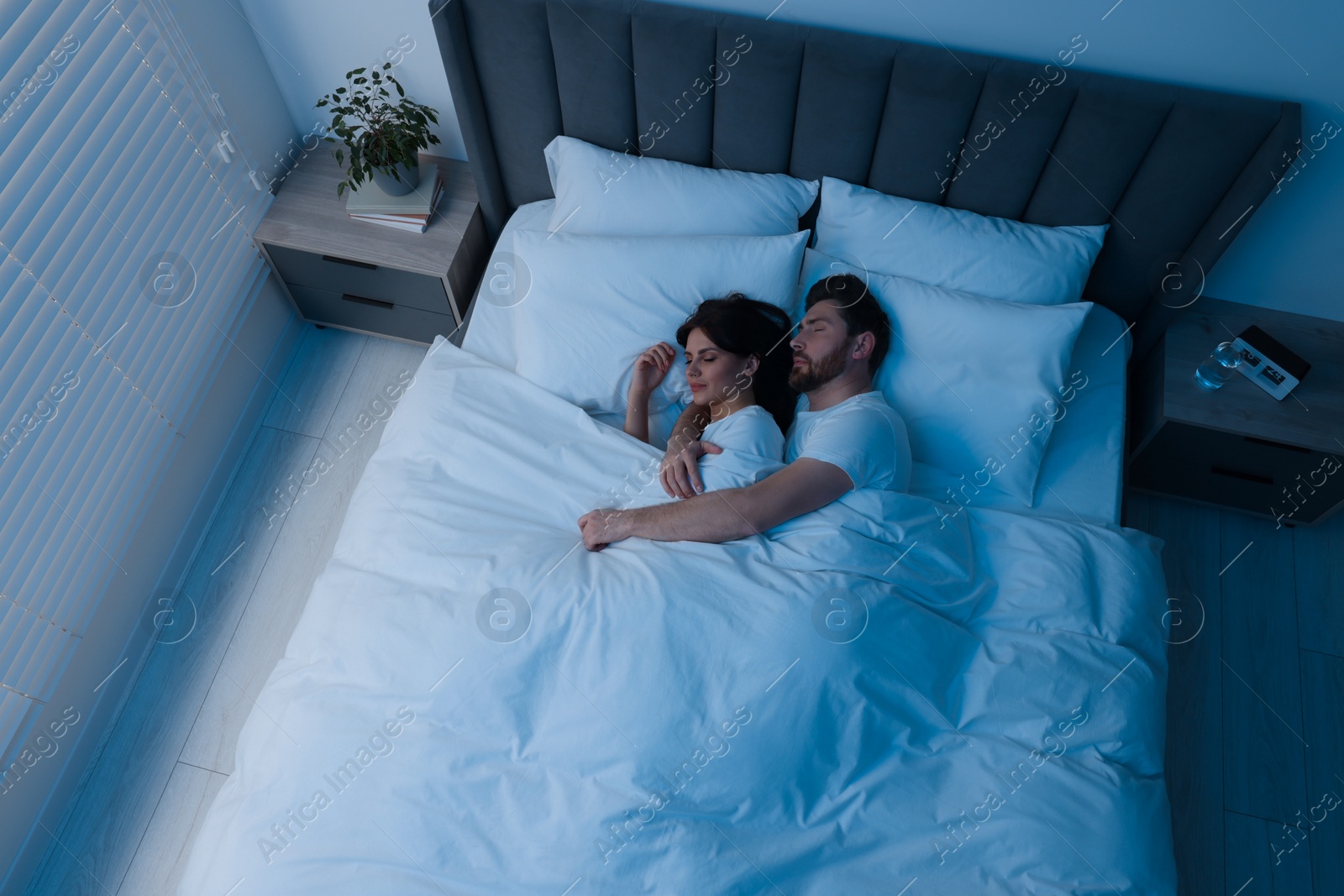 Photo of Lovely couple sleeping together in bed at night, top view