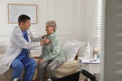 Photo of Caregiver examining senior woman in room. Home health care service