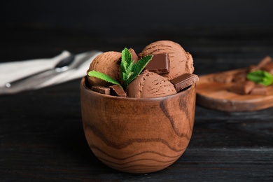 Photo of Wooden bowl of chocolate ice cream and mint on dark table