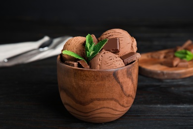 Wooden bowl of chocolate ice cream and mint on dark table