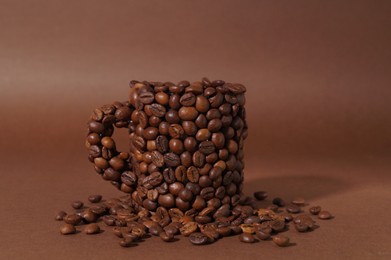 Cup made of coffee beans on brown background