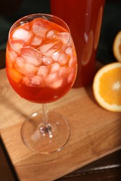 Photo of Aperol spritz cocktail and ice cubes in glass and bottle on wooden table, closeup