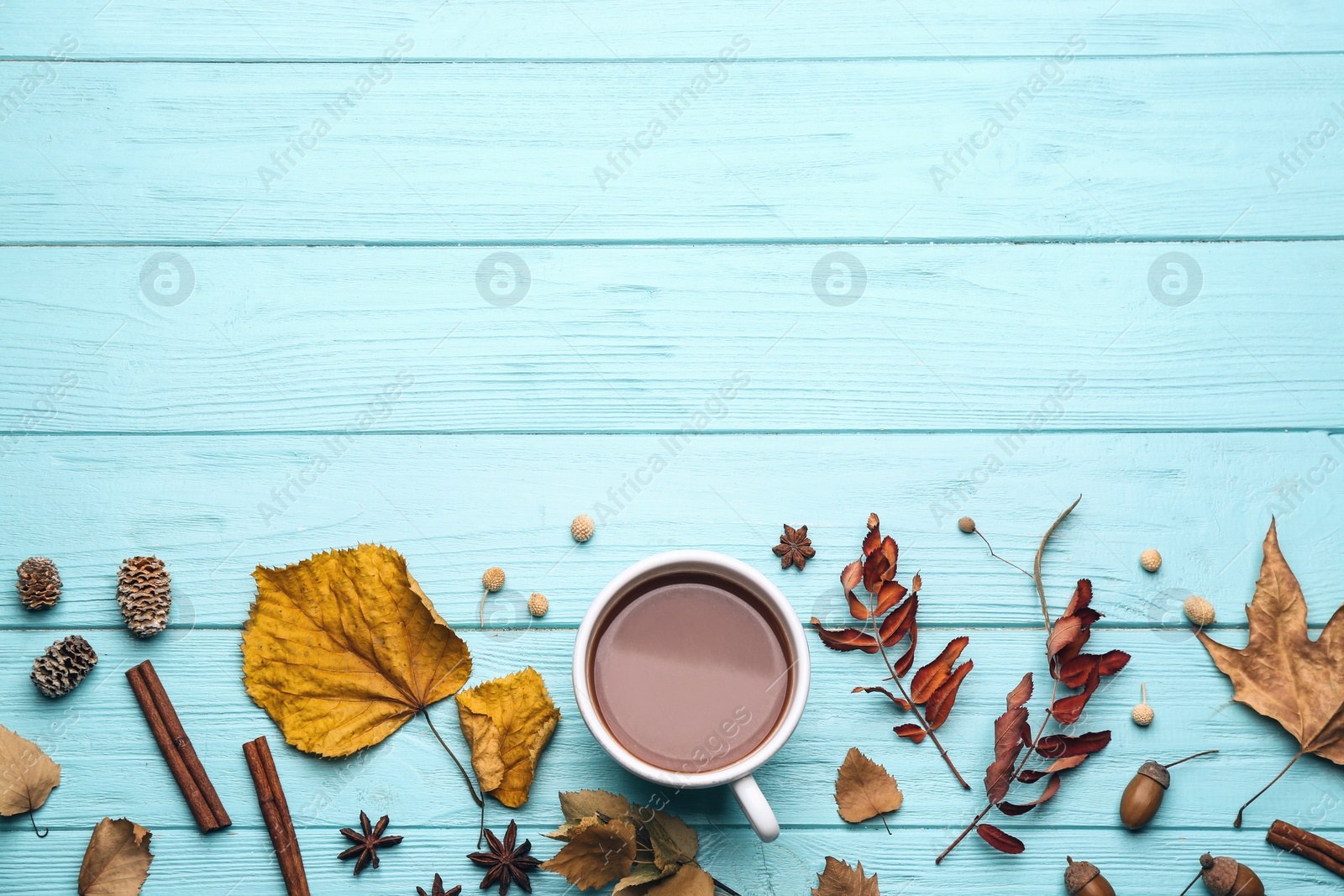 Photo of Flat lay composition with cup of hot drink and autumn leaves on light blue wooden table, space for text. Cozy atmosphere