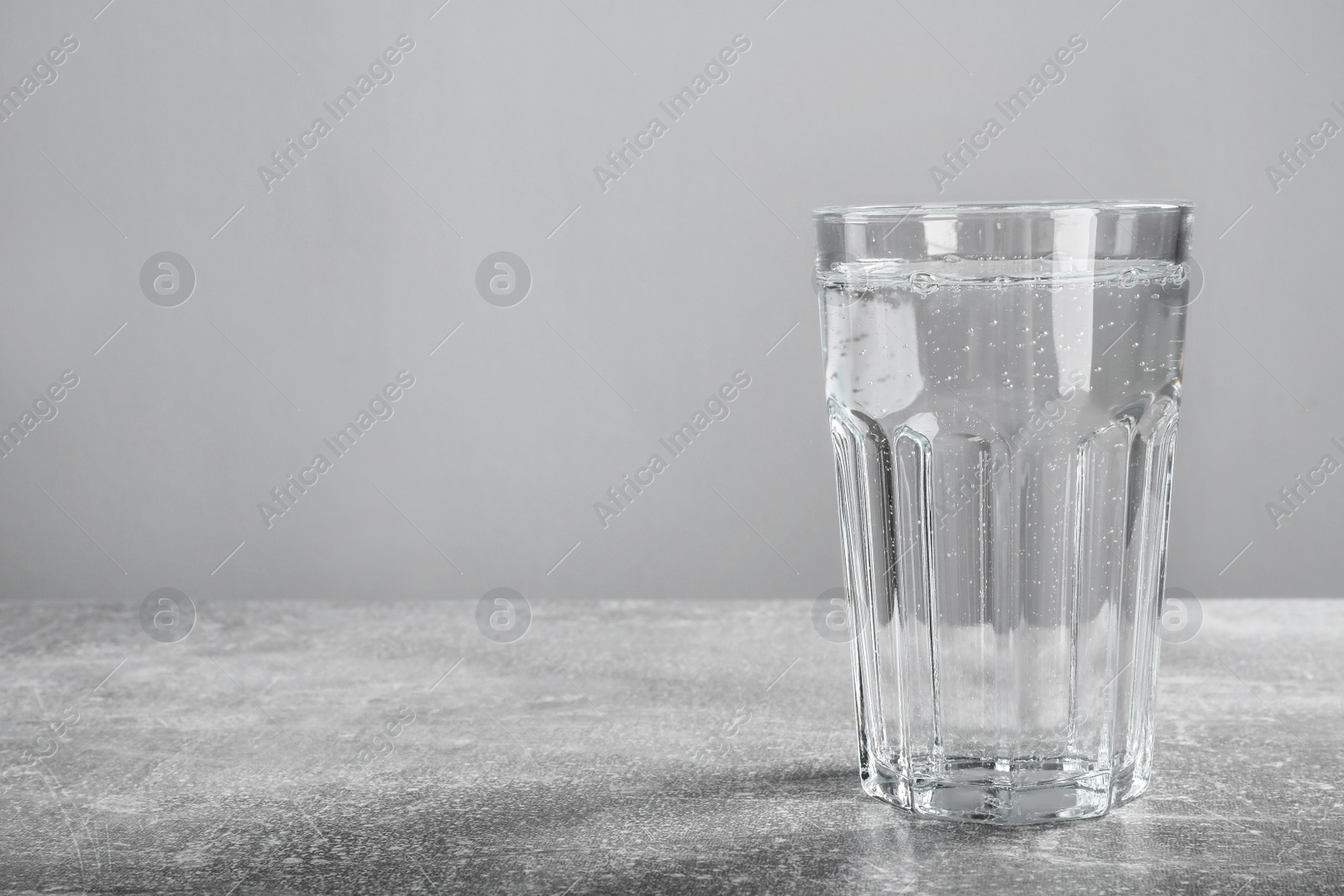 Photo of Glass of soda water on grey background. Space for text