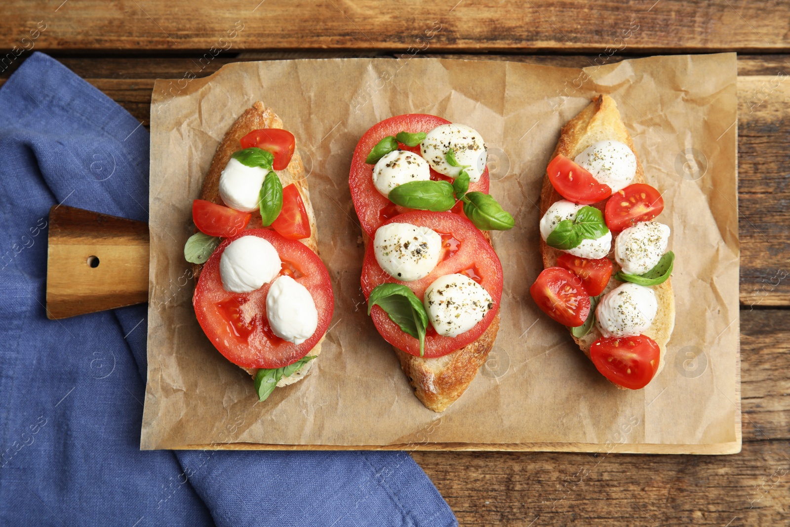 Photo of Delicious sandwiches with mozzarella, fresh tomatoes and basil on wooden table, flat lay