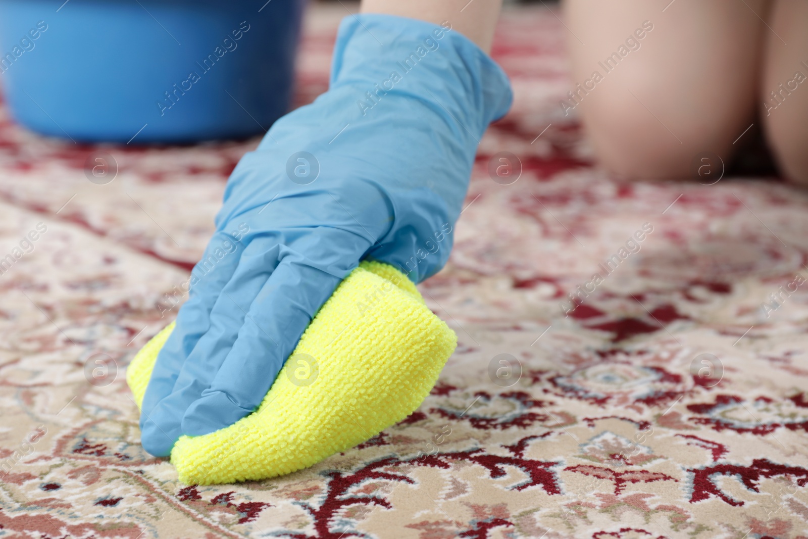 Photo of Woman in rubber gloves cleaning carpet with rag indoors, closeup