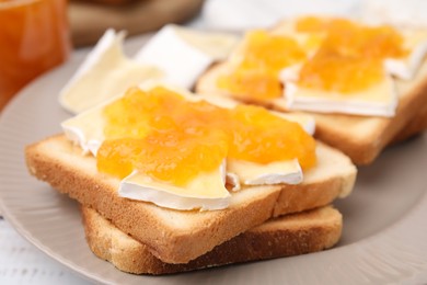 Photo of Tasty sandwiches with brie cheese and apricot jam on plate, closeup