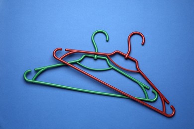 Photo of Empty clothes hangers on blue background, flat lay