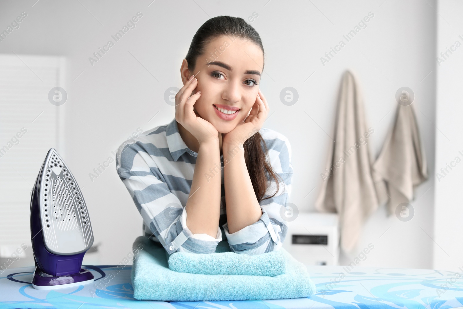 Photo of Young woman with electric iron at home