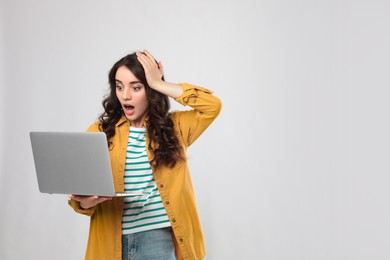 Photo of Shocked young woman with laptop on white background