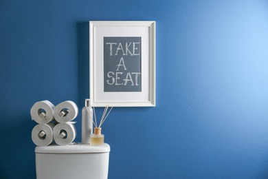 Photo of Decor elements, necessities and toilet bowl near blue wall. Bathroom interior