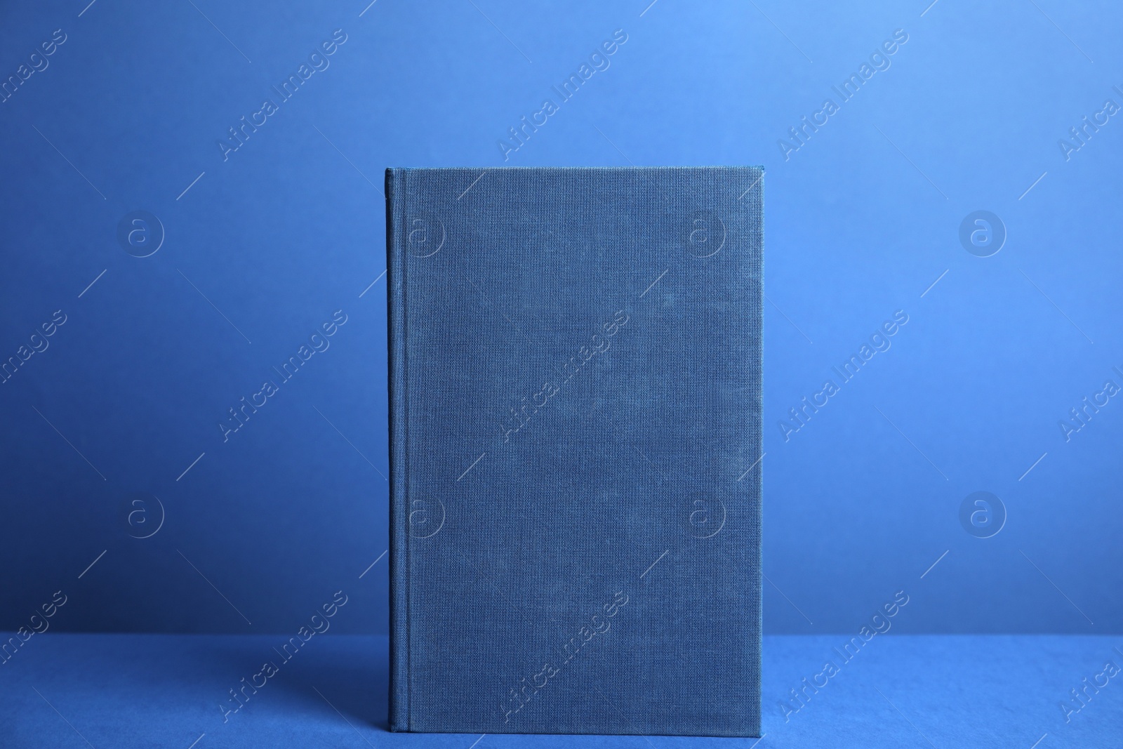 Photo of Hardcover book on blue background. Space for design