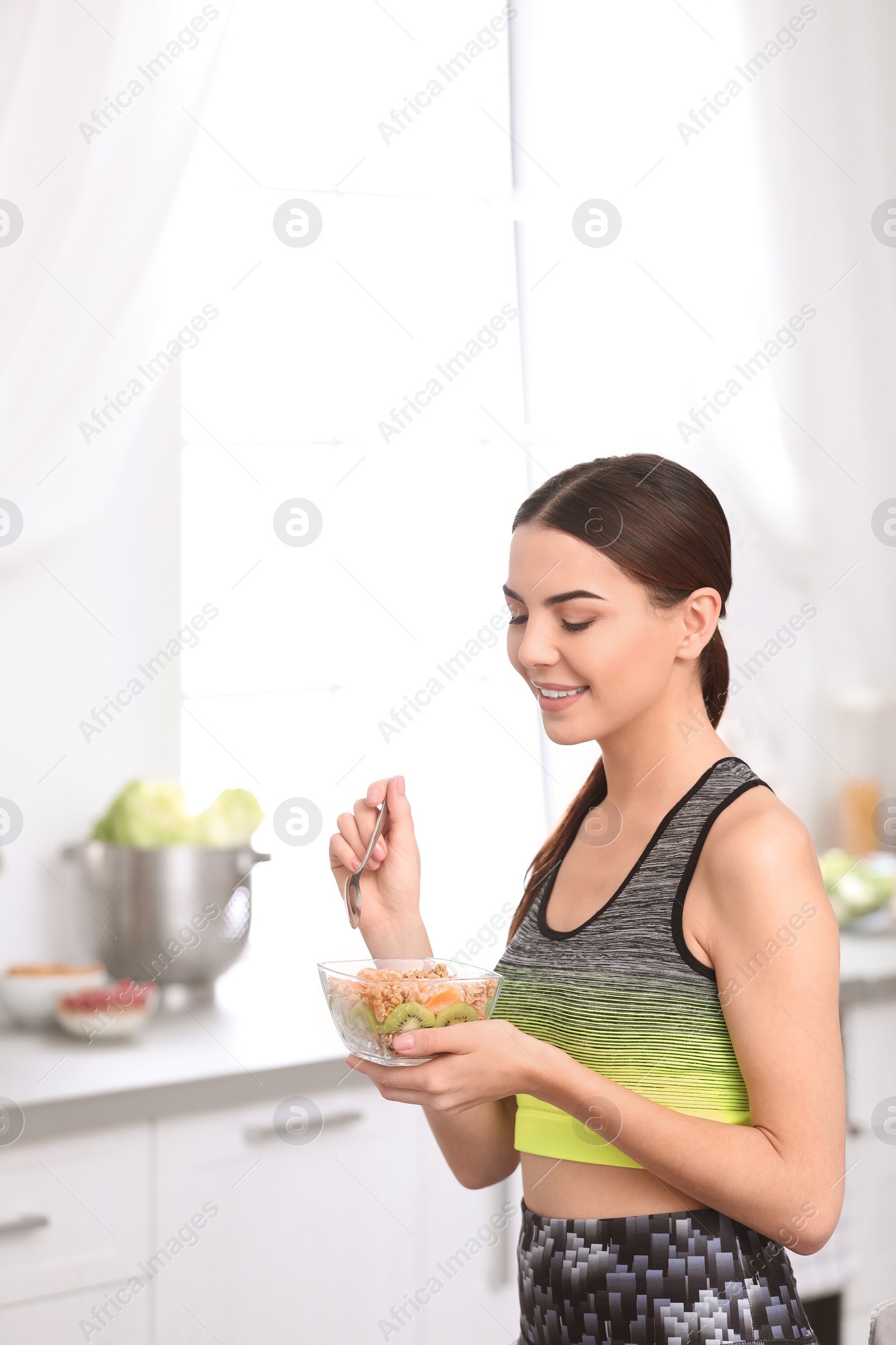 Photo of Young woman in fitness clothes having healthy breakfast at home