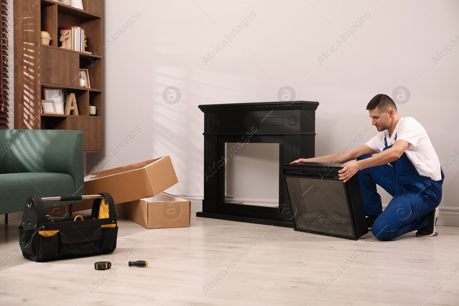 Photo of Professional technician installing electric fireplace in room