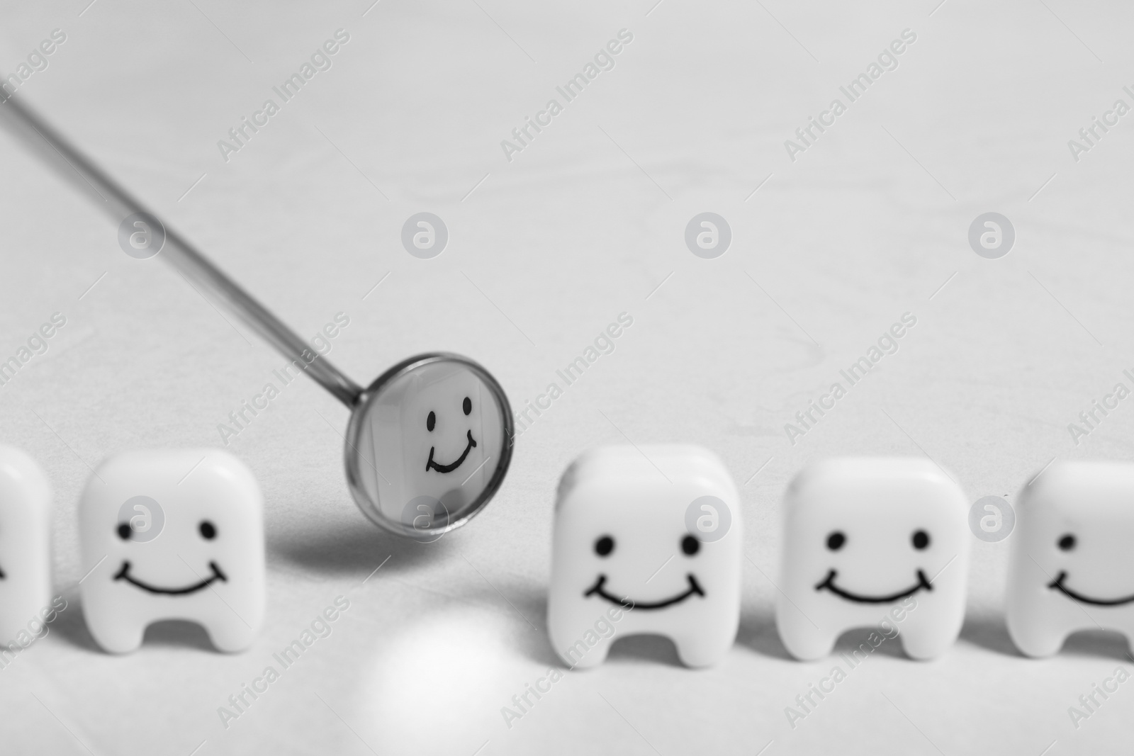 Photo of Small plastic teeth and dental mirror on table, closeup