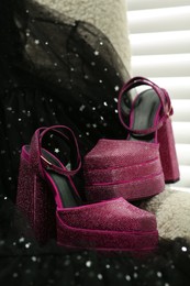 Photo of New pink high heeled shoes with platform and square toes on soft armchair indoors
