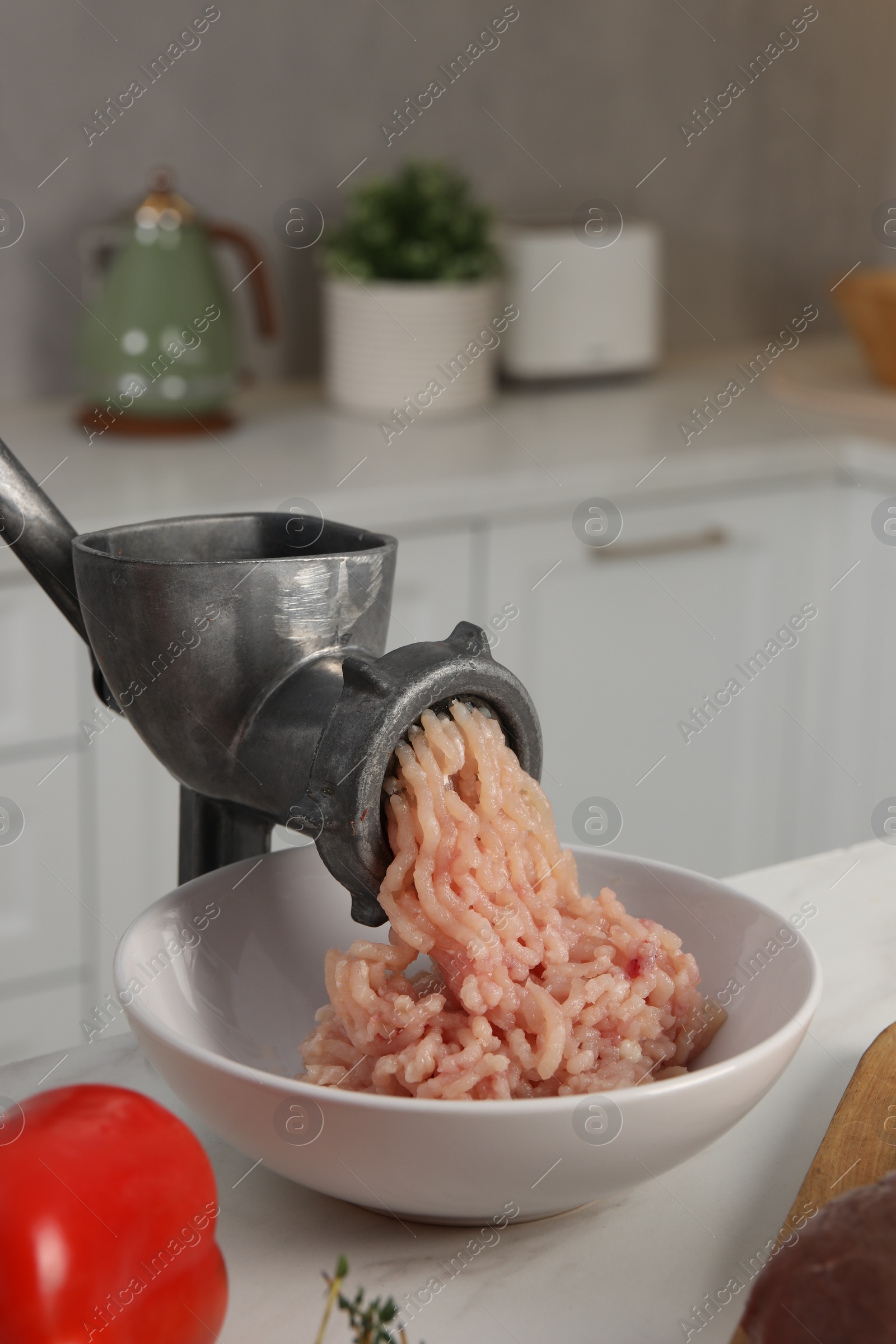 Photo of Metal meat grinder with chicken mince and products on white table in kitchen