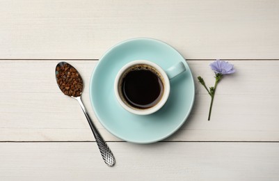 Cup of delicious chicory drink, granules and flower on white wooden table, flat lay