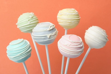 Photo of Sweet colorful cake pops on orange background