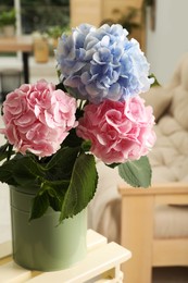 Photo of Beautiful hortensia flowers in can on stand indoors