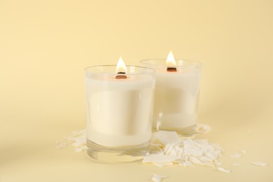 Photo of Burning soy candles and wax flakes on beige background