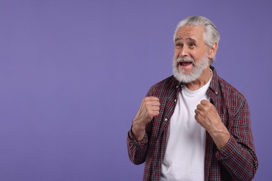 Emotional senior sports fan on purple background, space for text