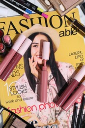 Photo of Bright lip glosses and fashion magazine on table, flat lay