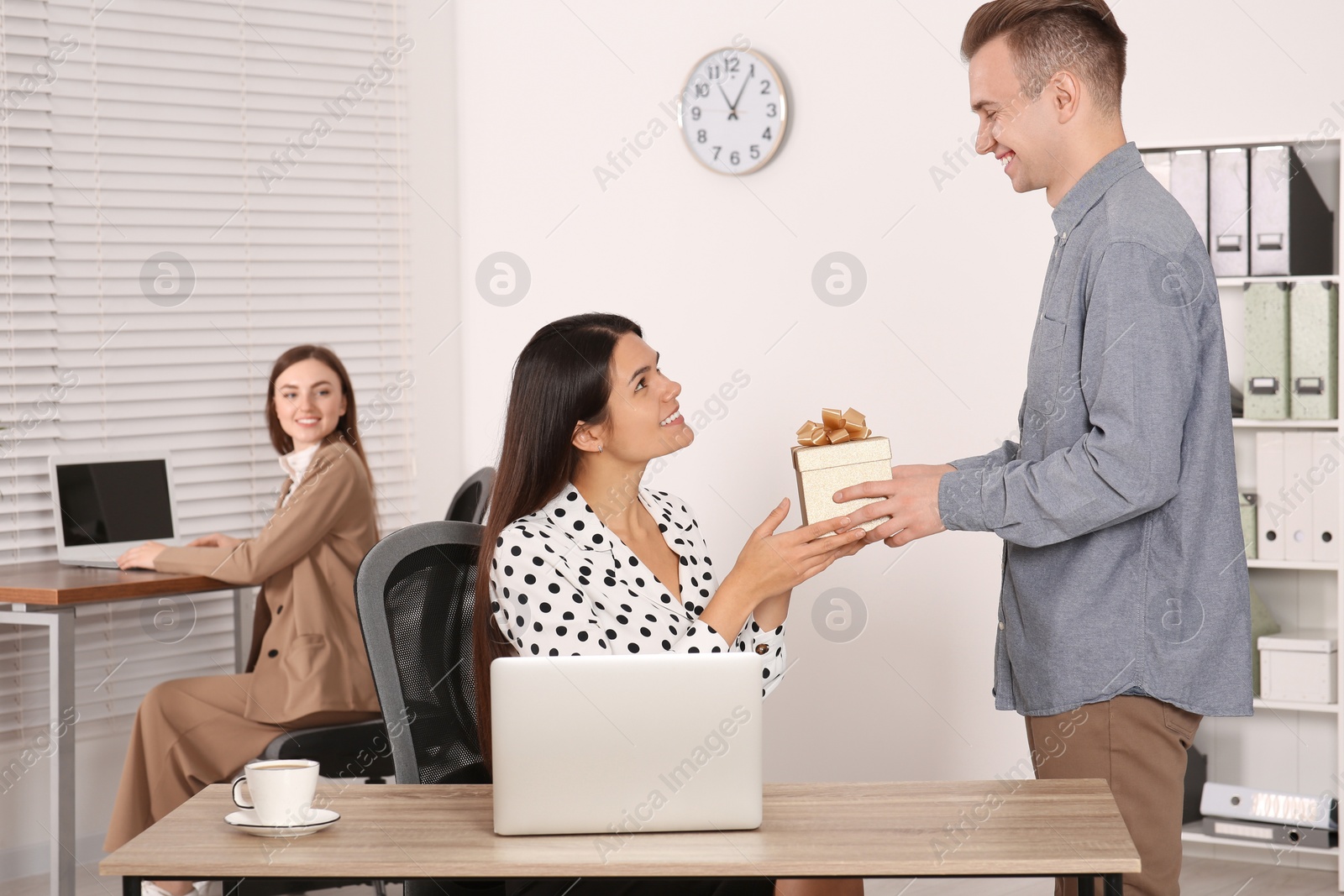 Photo of Man presenting gift to his colleague in office