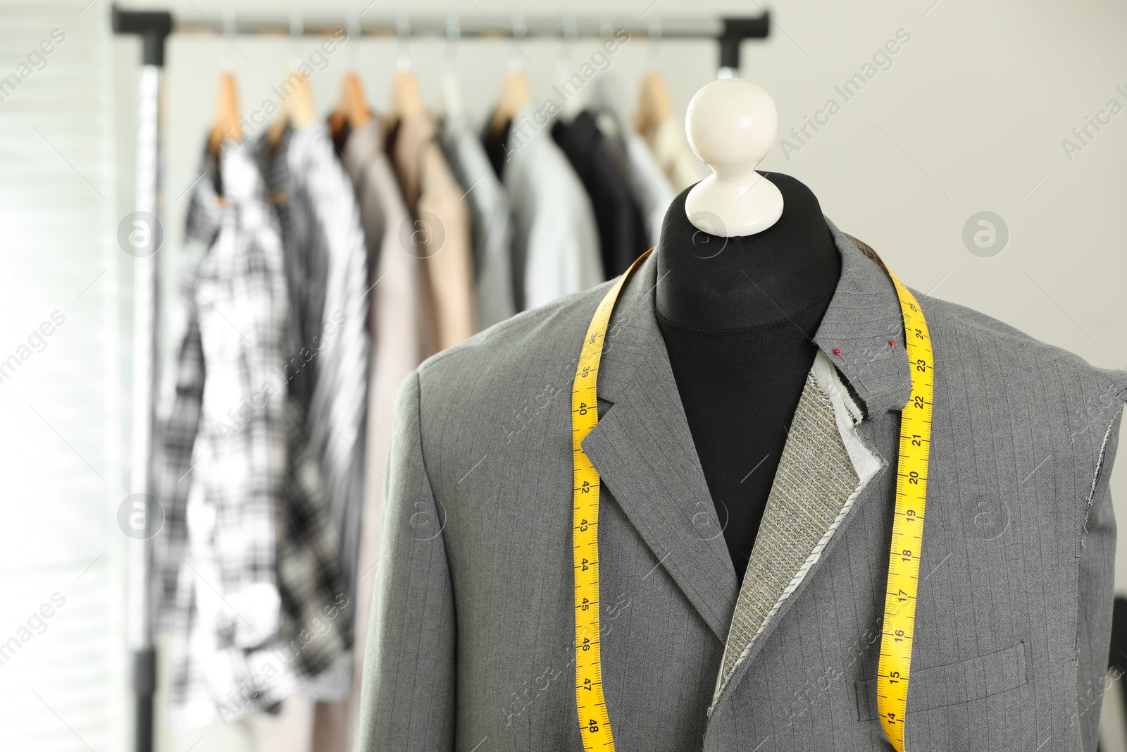 Photo of Mannequin with unfinished jacket and measuring tape in tailor shop, closeup. Space for text