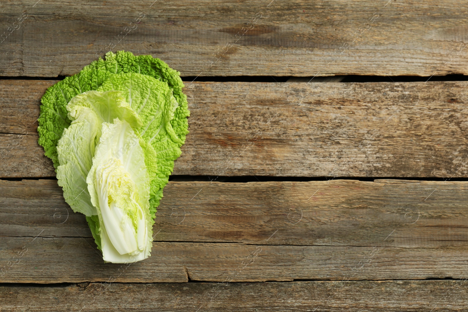 Photo of Cut fresh Chinese cabbage on wooden table, top view. Space for text