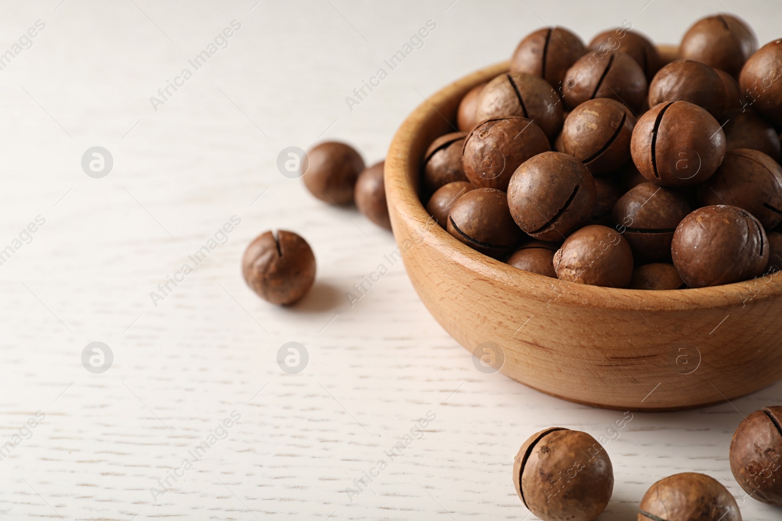 Photo of Bowl with organic Macadamia nuts on white table