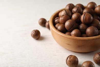 Photo of Bowl with organic Macadamia nuts on white table