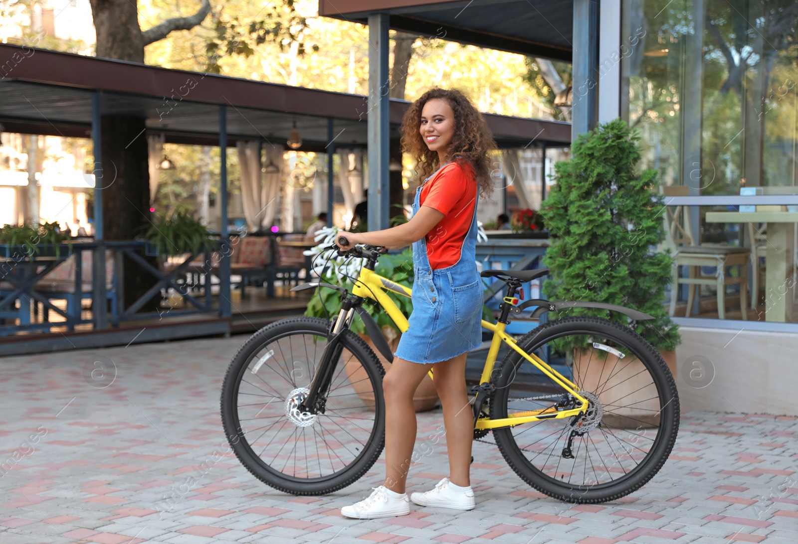 Photo of Beautiful young African-American woman with bicycle on city street