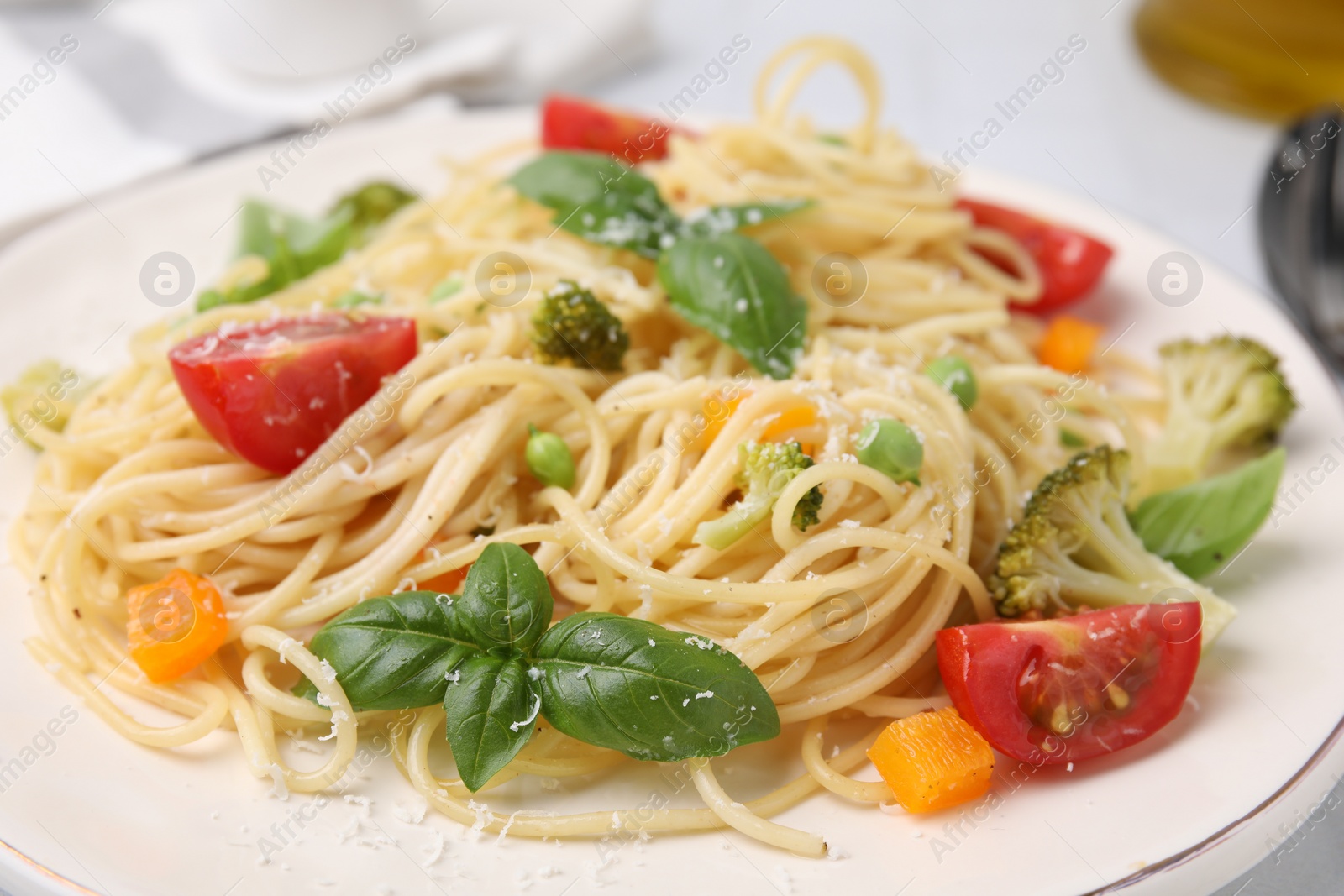 Photo of Delicious pasta primavera with tomatoes, basil and broccoli on plate, closeup