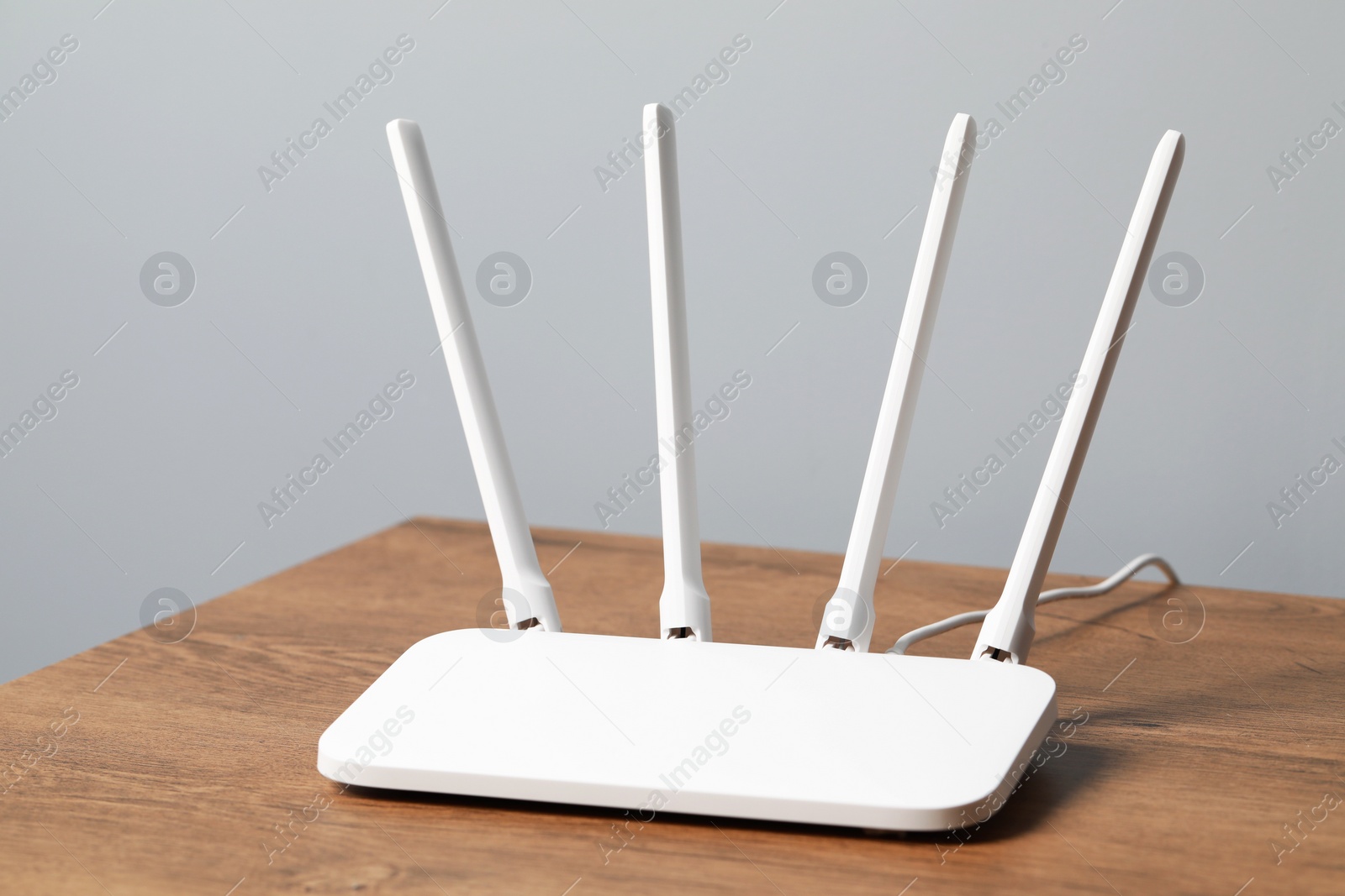 Photo of New white Wi-Fi router on wooden table indoors