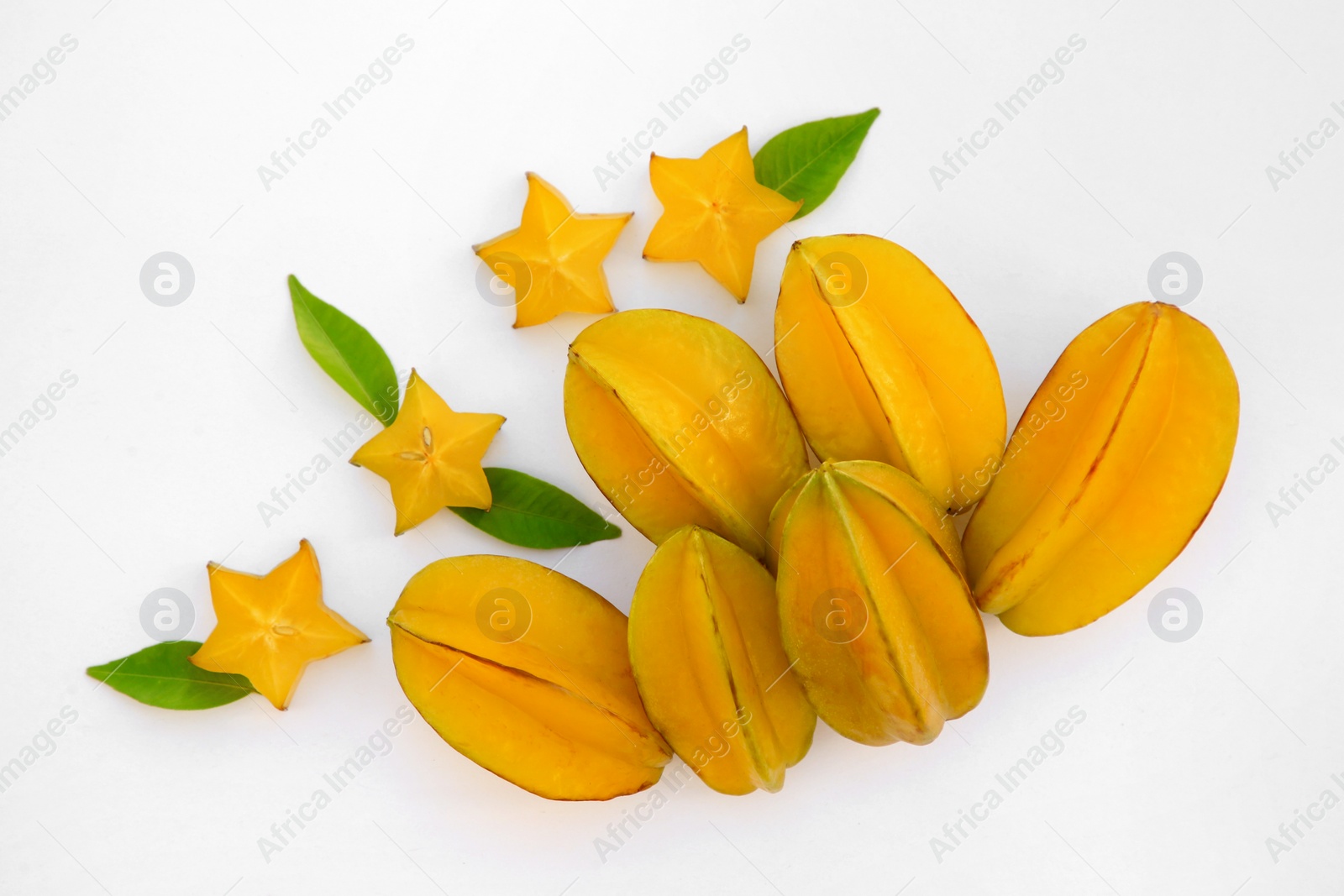 Photo of Delicious cut and whole carambolas, green leaves on white background, top view