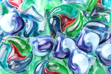 Many different laundry capsules as background, top view