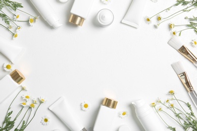 Flat lay composition with different cosmetic products, beauty accessories and chamomile flowers on white table. Space for text