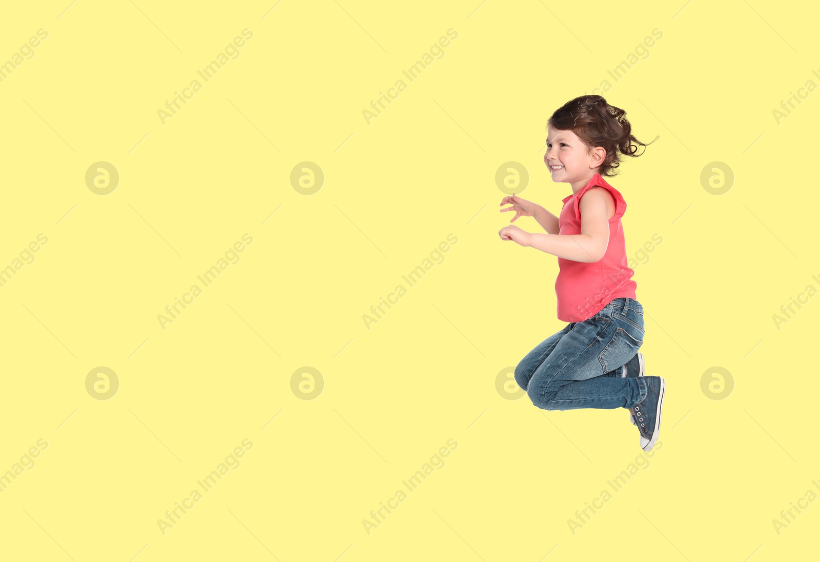 Image of Cute girl jumping on light yellow background, space for text