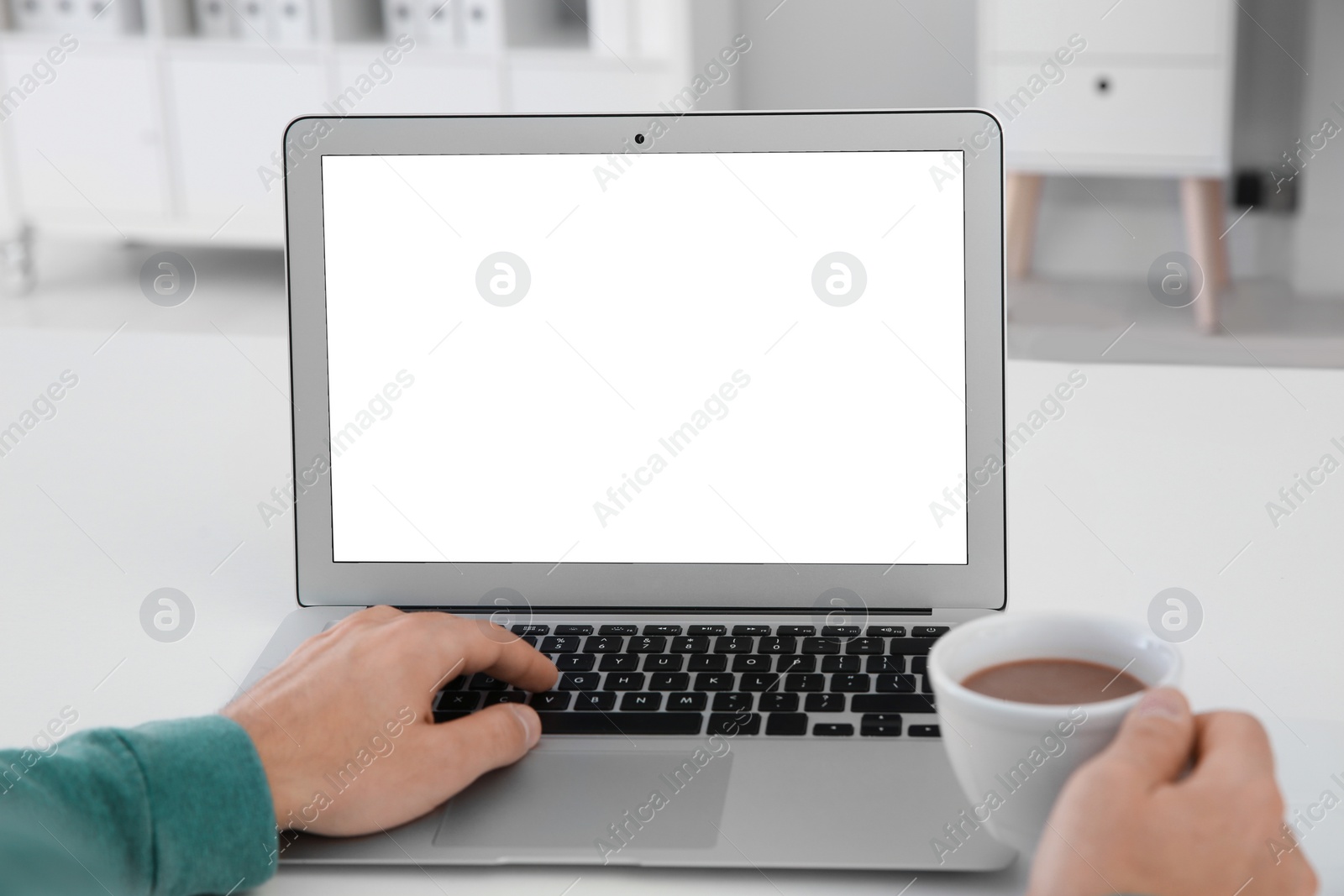 Photo of Young man working with modern laptop at table, closeup. Mockup for design