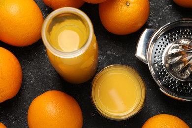 Photo of Tasty fresh oranges and juice on black table, flat lay
