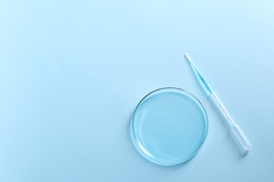 Photo of Transfer pipette and petri dish on light blue background, top view. Space for text