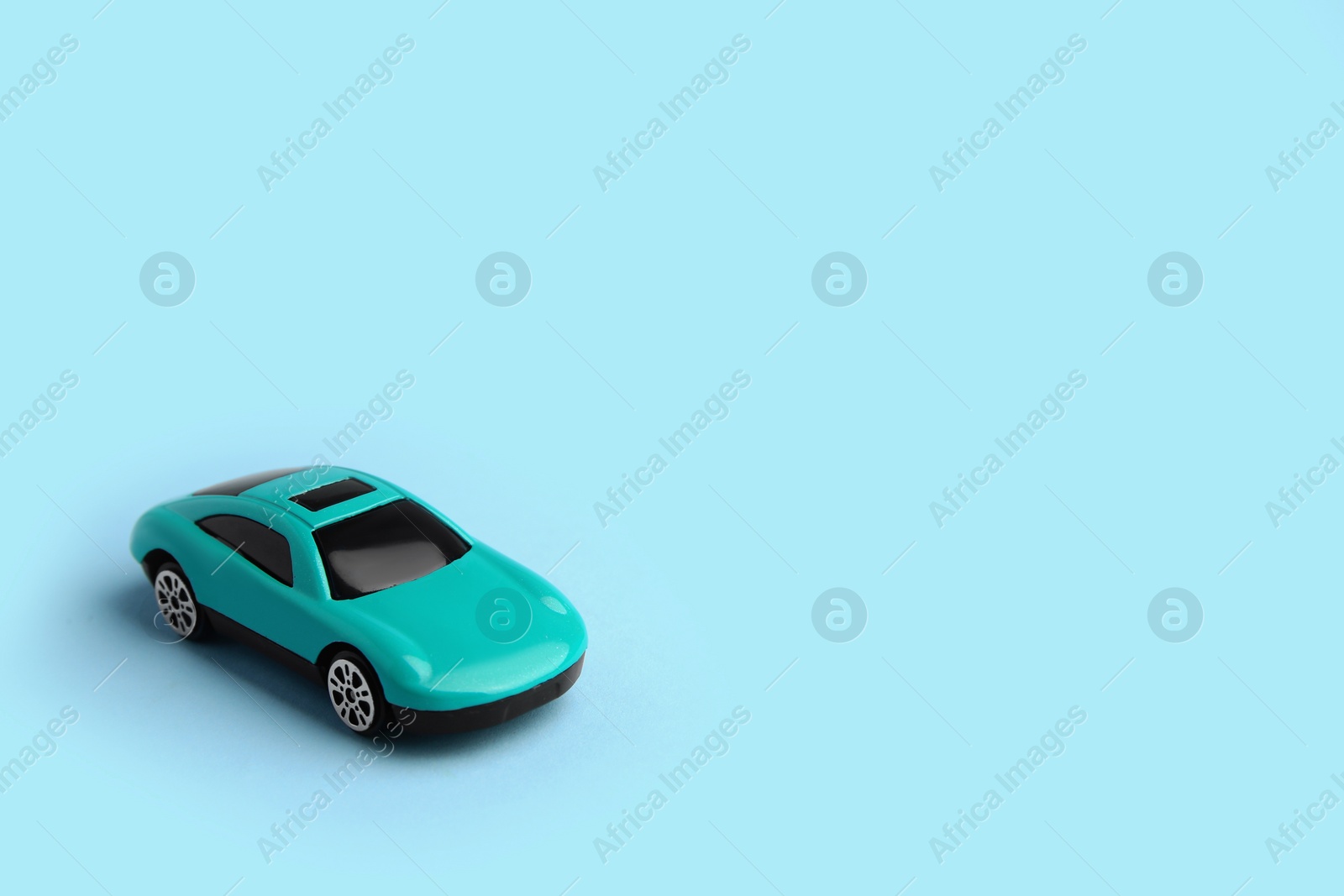 Photo of One bright car on light blue background, space for text. Children`s toy