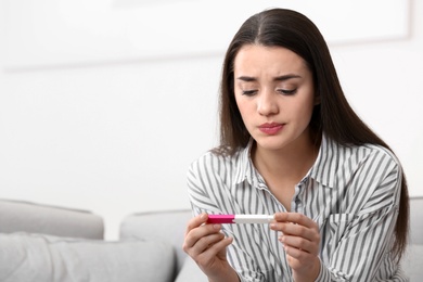 Photo of Young woman with pregnancy test at home. Gynecology and childbirth