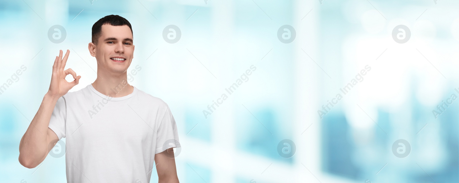 Image of Man with clean teeth smiling and showing ok gesture on blurred background, space for text. Banner design