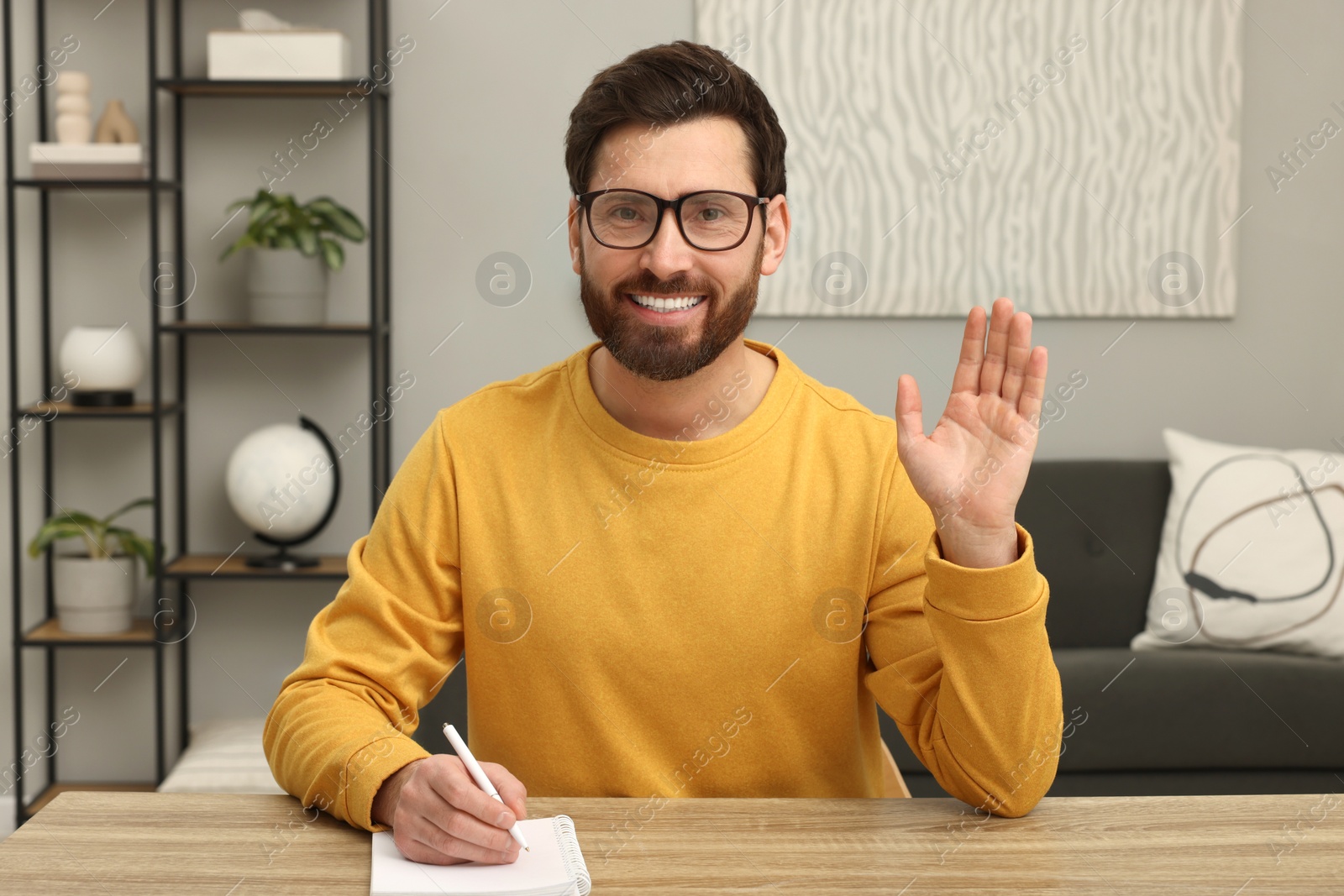 Photo of Stylish man greeting someone at wooden table indoors