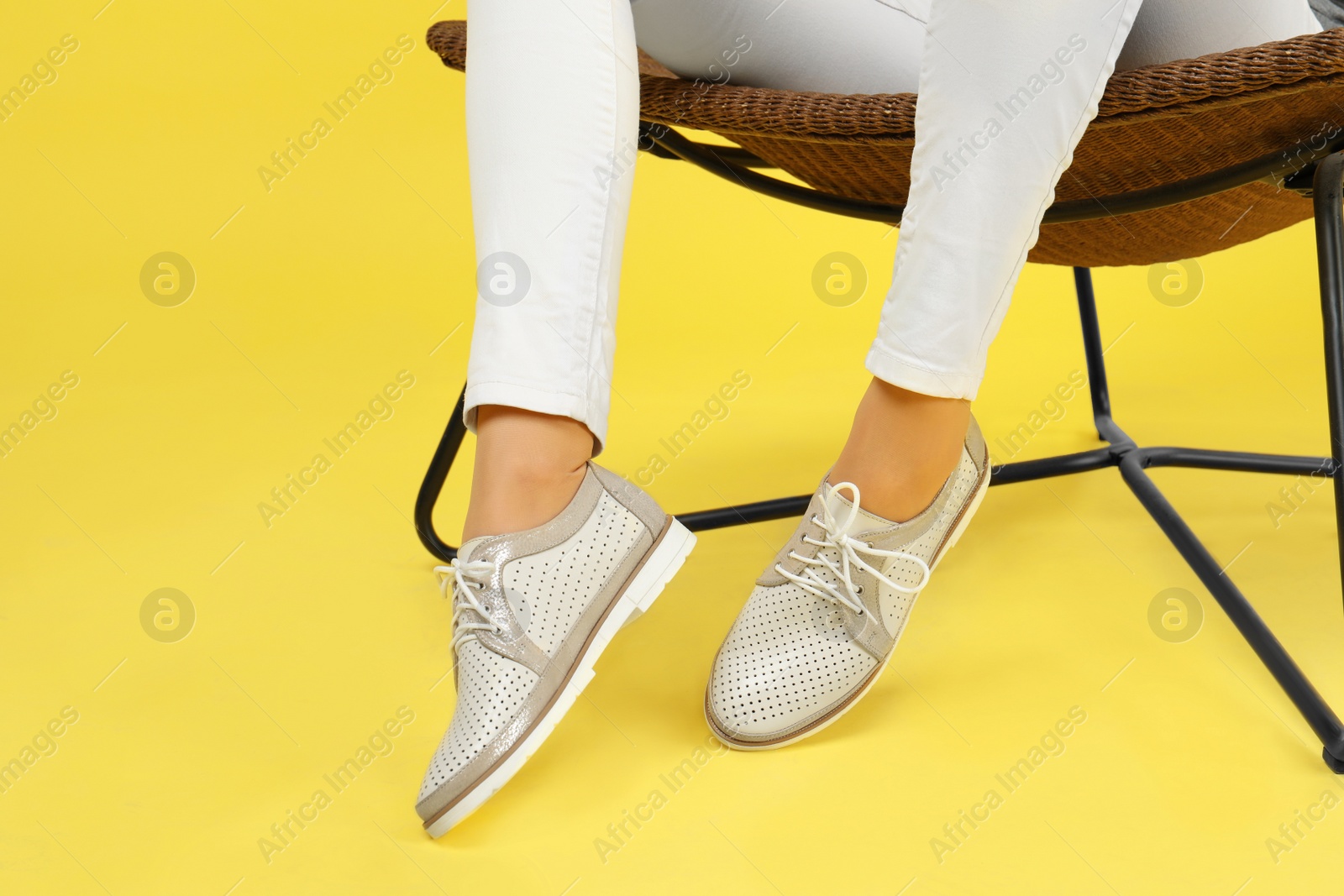 Photo of Woman in stylish shoes sitting on chair, color background