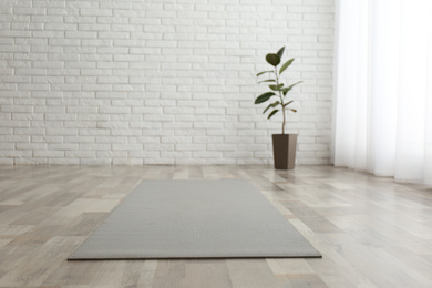 Photo of Unrolled grey yoga mat on floor in room