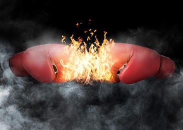 Boxing gloves with flame opposing each other against black background
