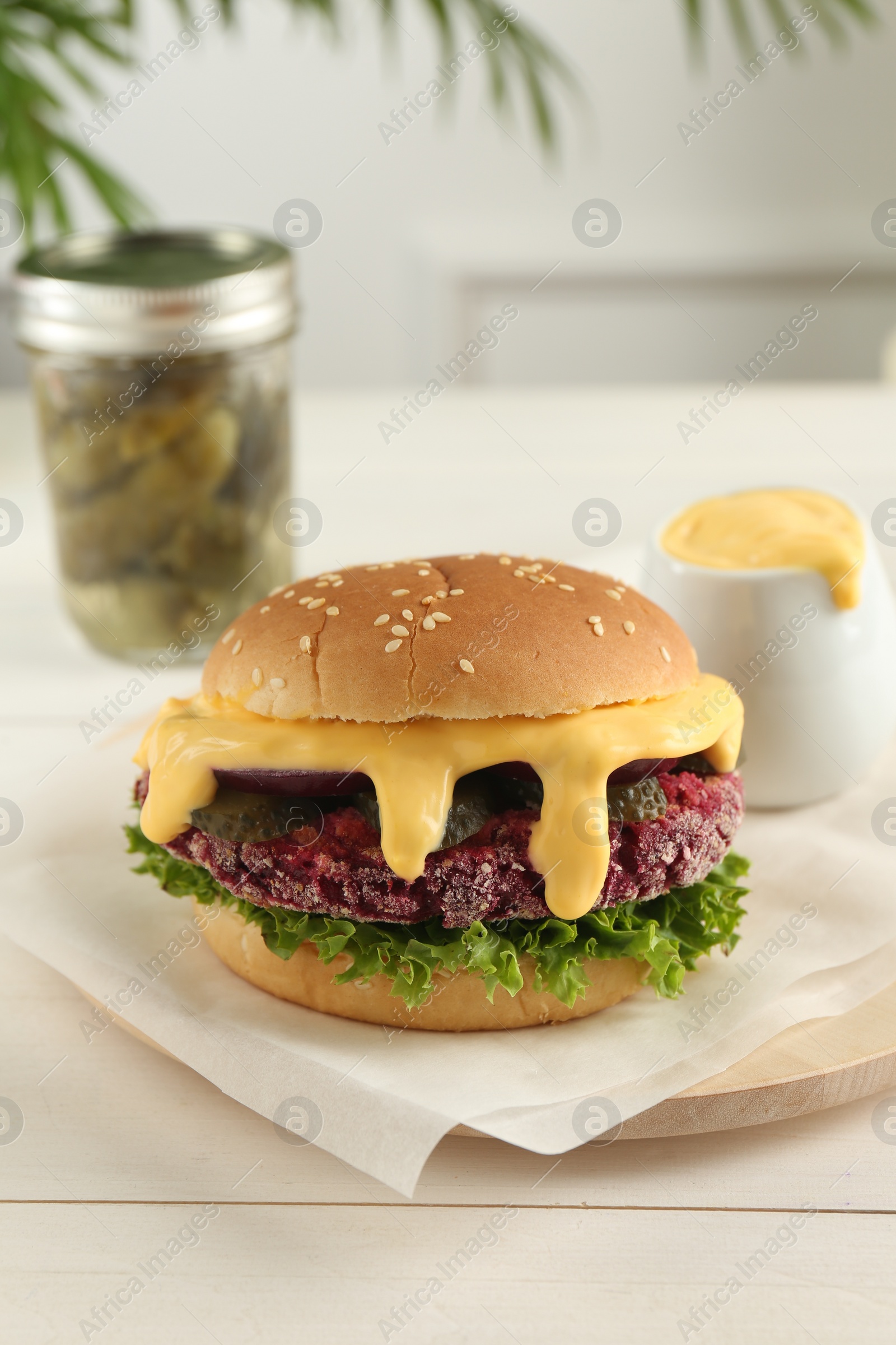 Photo of Tasty vegetarian burger with beet patty on white wooden table